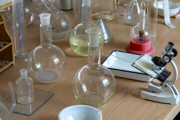 Vintage microscope and glass flasks on a laboratory table. Retro chemistry equipment including...