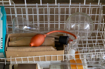 Glass aspirator with rubber bulb and laboratory stopper, placed on a metal shelf. Vintage chemistry...