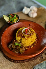 A beautifully presented Beef Khichuri With Green Salad dish with a side of salad and a lemon wedge, served on a rustic wooden surface.
