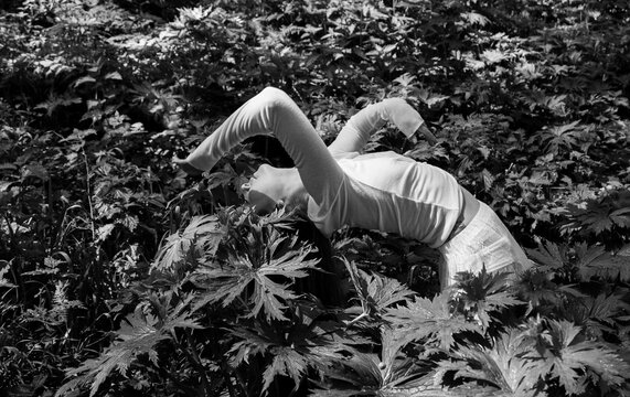 Woman bending backward in dense foliage