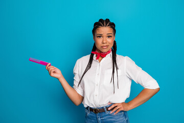 Young woman with braided hair holding a pink comb against a bright blue background, showcasing...
