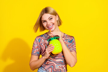 Smiling young woman with short blonde hair holding a pineapple-shaped tumbler against a vibrant...