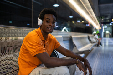 Young man listening to music with headphones while waiting for subway train