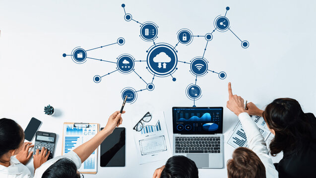 A group of professionals engages in a collaborative session on cloud computing, utilizing laptops and charts to highlight digital transformation and strategic insights. Amity