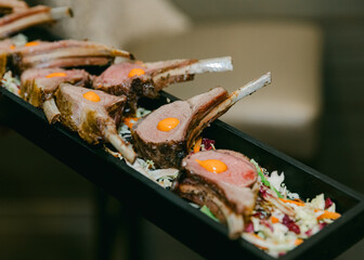 Exquisite lamb chops garnished with fresh ingredients and egg yolks presented elegantly on a wooden platter