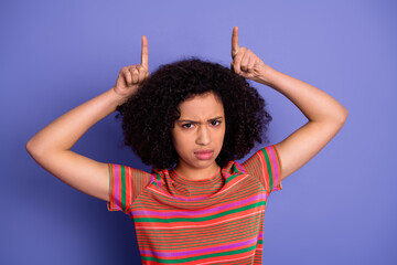 Young woman in colorful casual shirt making playful hand gestures against a vivid violet background