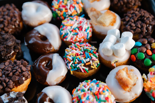 Colorful miniature donuts arranged on a black platter at a festive gathering in the afternoon