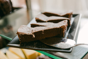 Delicious chocolate dessert slices served on a black plate in a cozy bakery setting during daylight