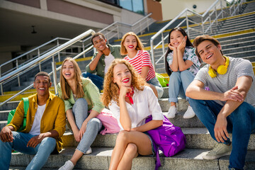 Young friends sitting on outdoor steps enjoying a sunny day and bonding in a lively urban setting