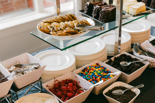 Dessert buffet featuring cookies, candies, and toppings at an indoor gathering during afternoon hours