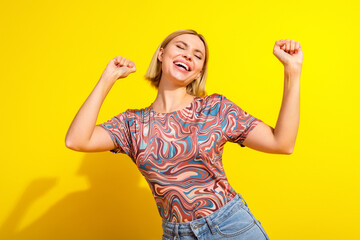 Cheerful young woman with blonde hair in stylish printed top enjoying her day, posing against a...