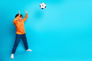 Energetic young boy playing with a soccer ball against a bright blue background, showcasing...