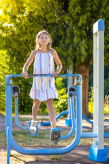 Young girl exercising on outdoor exercise machines. Woman exercising outdoors in the city park. Healthy lifestyle on city playground