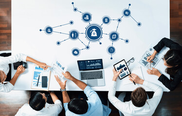 A diverse business team collaborates over a table, analyzing graphs and data visualizations while...