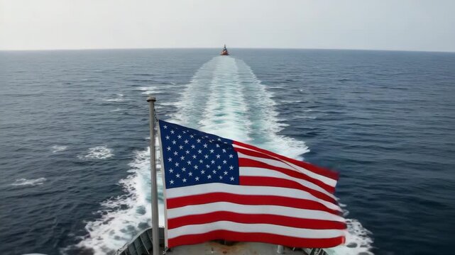 American flag waving at sea with ship's wake in background  