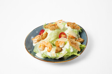 Salad with shrimp, iceberg lettuce, cherry tomatoes, wheat croutons, and creamy dressing on a plate, isolated on white background