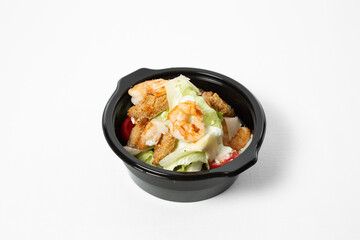 Salad with shrimp, iceberg lettuce, cherry tomatoes, wheat croutons, and creamy dressing on a plate, isolated on white background
