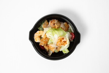 Salad with shrimp, iceberg lettuce, cherry tomatoes, wheat croutons, and creamy dressing on a plate, isolated on white background