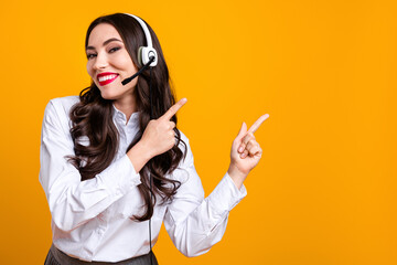 Confident businesswoman in a headset pointing to the side on a vibrant yellow background with a...