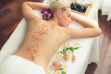 Woman customer having exfoliation treatment in luxury spa salon with warmth candle light ambient....