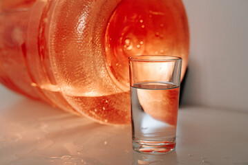 Glass being filled by orange jug, minimalist aesthetic with motion and color contrast.
