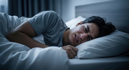 A stressed man suffering from a nightmare in his bed at night. Sleep problem, insomnia, or bad dream concept.