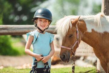 Cute little girl petting a pony in a farm