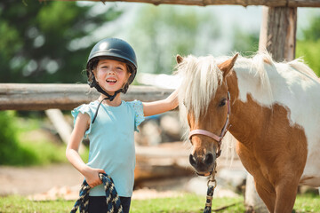 Cute little girl petting a pony in a farm