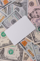 The white plastic card as a symbol of cashless payments on the background of cash paper money of USA