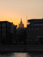Beautiful sunset over city skyline with iconic tower rising above buildings near a river