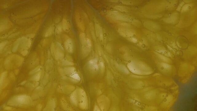 Bubbly orange slice submerged in sparkling water under bright blue background