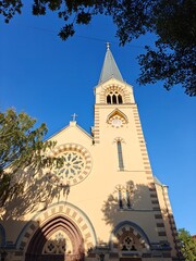 Historic church with stained glass windows and a tall steeple under a clear blue sky in a tranquil setting