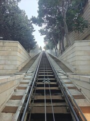 Scenic uphill railway tracks leading through trees towards the top of a hill during daylight