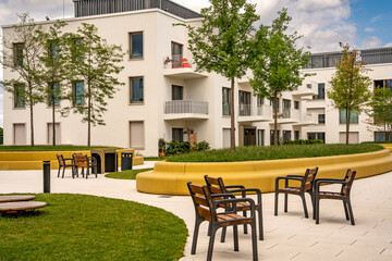 Modern Architecture In Freiham Munich Bavaria: Minimalist Building With Geometric Facade, Large Windows, And Small Tree In Courtyard Under Cloudy Sky