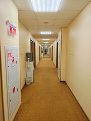 Long corridor in a beige-toned building with wooden doors and well-lit ceiling during daytime