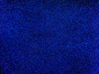Dark blue surface with a texture consisting of sequins. Festive abstract background, reminiscent of space and the universe with stars.