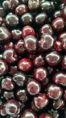 Close-up shot showcasing the rich, deep red color and shiny surfaces of fresh cherries, highlighting their plumpness and inviting texture, perfect for summer fruit themes