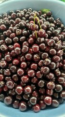 Delicious and ripe dark cherries in a blue bowl, fresh and juicy summer fruits for healthy eating and dessert, perfect for backgrounds and wallpapers .