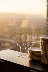 Glass goblets stand on a table in a restaurant against the background of a window and sunset