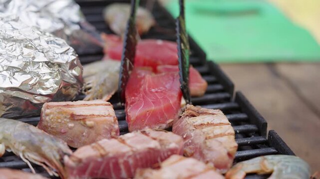 A chef tries to lift a grilled piece of tuna off the grill to turn it over.