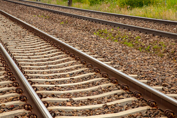 Naklejka premium Detailed view of parallel railway tracks with gravel ballast. Geometric pattern of rails and sleepers, infrastructure concept