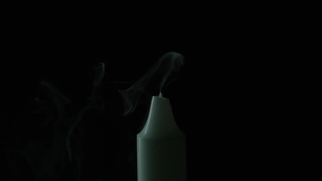 Wind gust snuffs candlelight in total darkness closeup. Wax taper flame fades