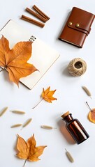Autumn flat lay with leaves, notebook, cinnamon sticks, and essential oil bottle setup