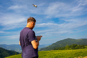 Man flying drone over scenic mountain landscape. A man operates a drone using a remote controller,...