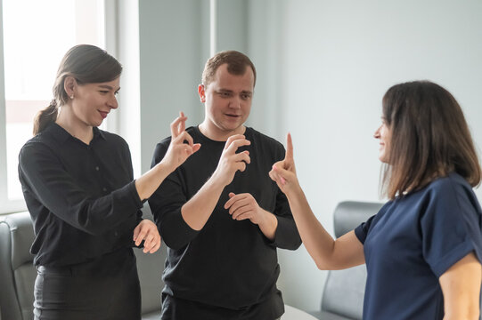 Caucasian woman teaching sign language to man and woman. 
