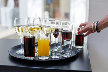 Assorted beverages on a tray served at a modern event during a bustling afternoon gathering