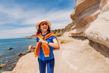 Happy tourist running joyfully across rocky cliffs by the sea, embracing the thrill of summer...