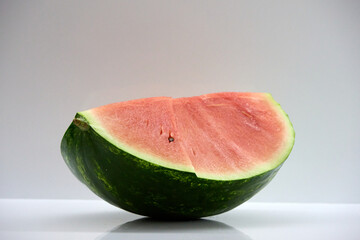 A Refreshing Slice of Watermelon: Close-up of a Juicy Watermelon Wedge on a White Surface,...
