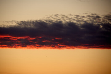 The dramatic sky at sunset with a striking red-orange horizon and dark, moody clouds above creates a powerful and atmospheric scene perfect for conveying a sense of awe and tranquility.