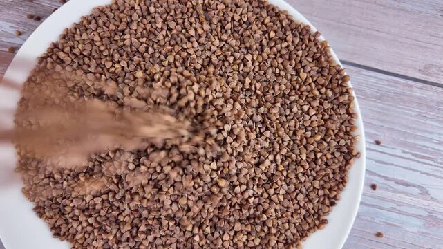 Falling buckwheat groats forming pile on wooden table